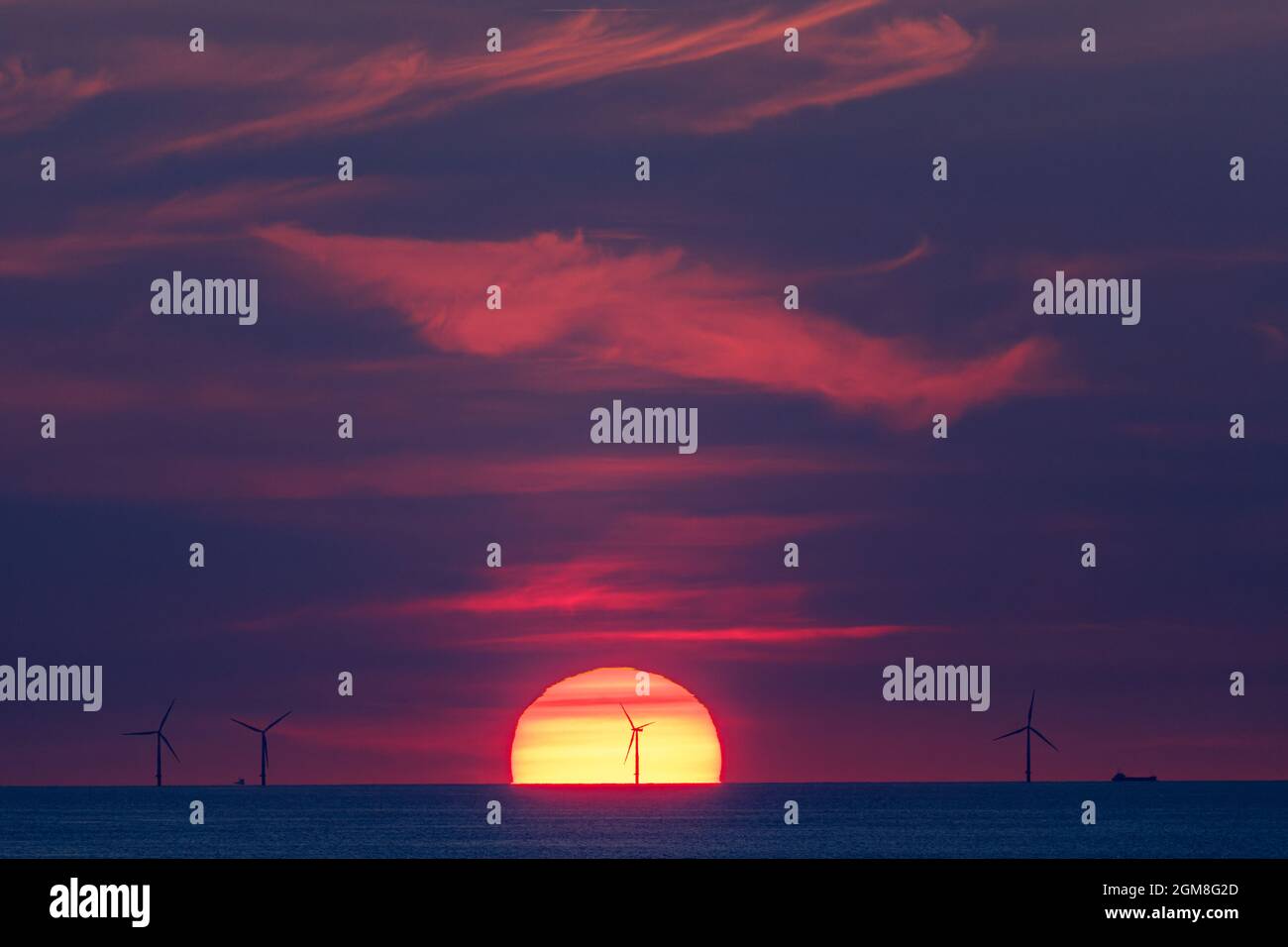 Offshore-Windpark in der Ostsee im Licht der untergehenden Sonne mit Schiffen Stockfoto