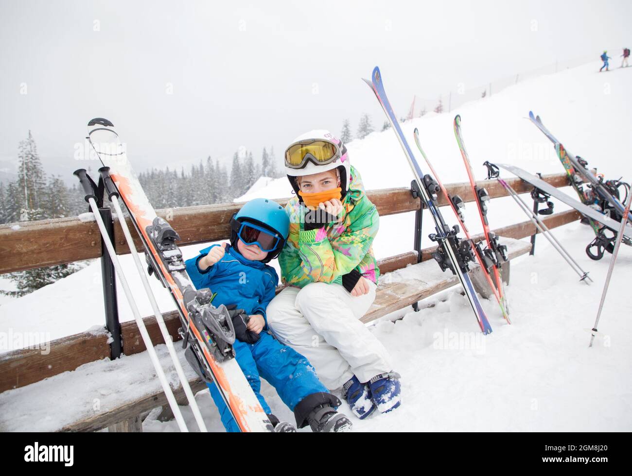 Kleinkind Junge und Teenager-Mädchen, Bruder und Schwester, ruhen auf der Bank und machen Pause vom Skifahren in den Bergen. Wintersport für die ganze Familie. Kindersk Stockfoto