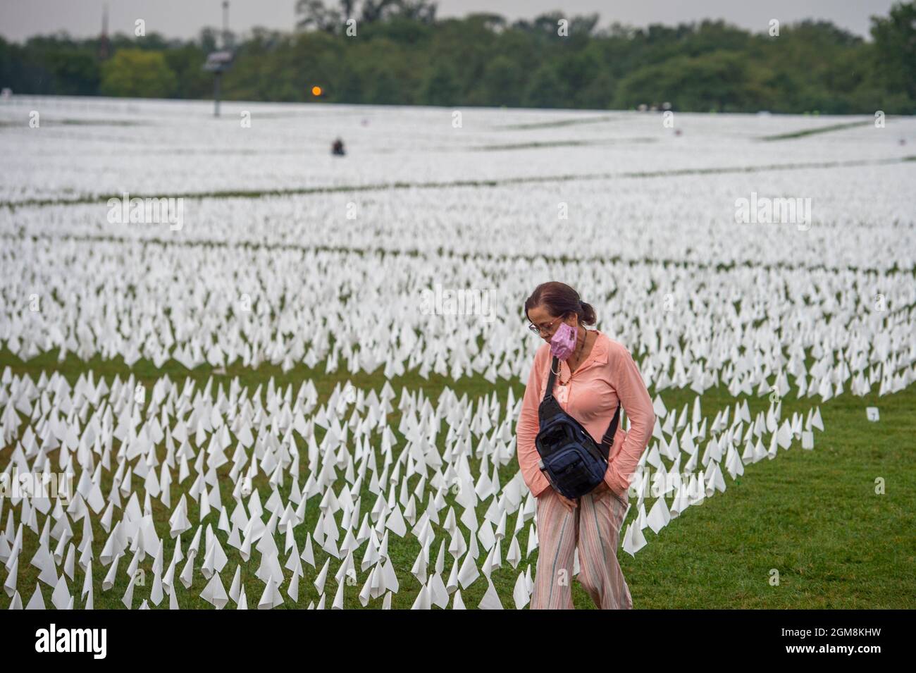 Am Donnerstag, den 16. September 2021, geht eine Frau in der National Mall in Washington, DC, auf einem Feld mit etwa 660,000 weißen Fahnen, die die Anzahl der durch Covid-19 verlorenen US-Opfer repräsentieren. Das Projekt der Künstlerin Suzanne Brennan Firstenberg mit dem Titel „in America: Remember“ wird vom 17. September 2021 bis zum 3. Oktober 2021 zu sehen sein. Kredit: Rod Lampey / CNP/Sipa USA Stockfoto