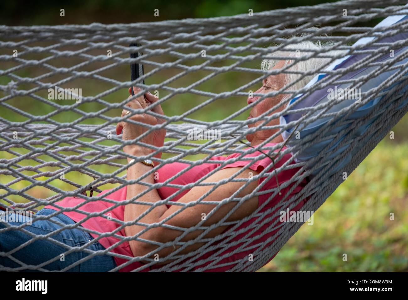 Prairieville, Michigan - Susan Newell, 72, liest im Urlaub von ihrem Kind aus, in einer Hängematte liegend. Stockfoto