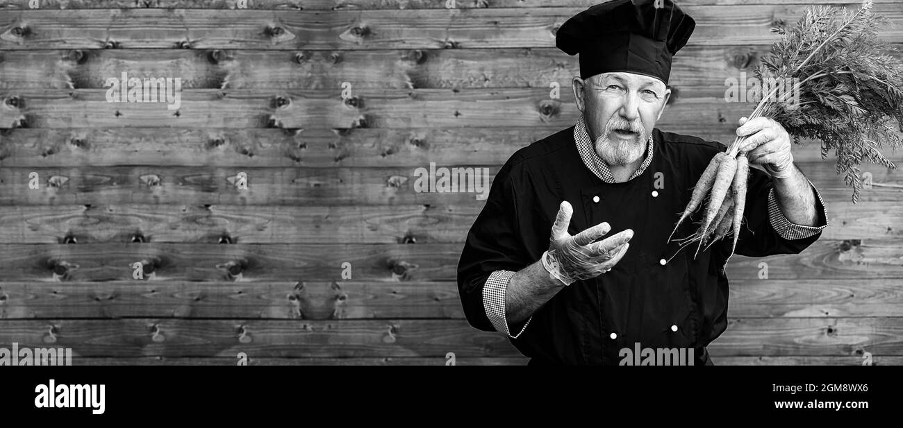 Landwirt in Uniform mit frischem Gemüse auf einem Holzboden Stockfoto