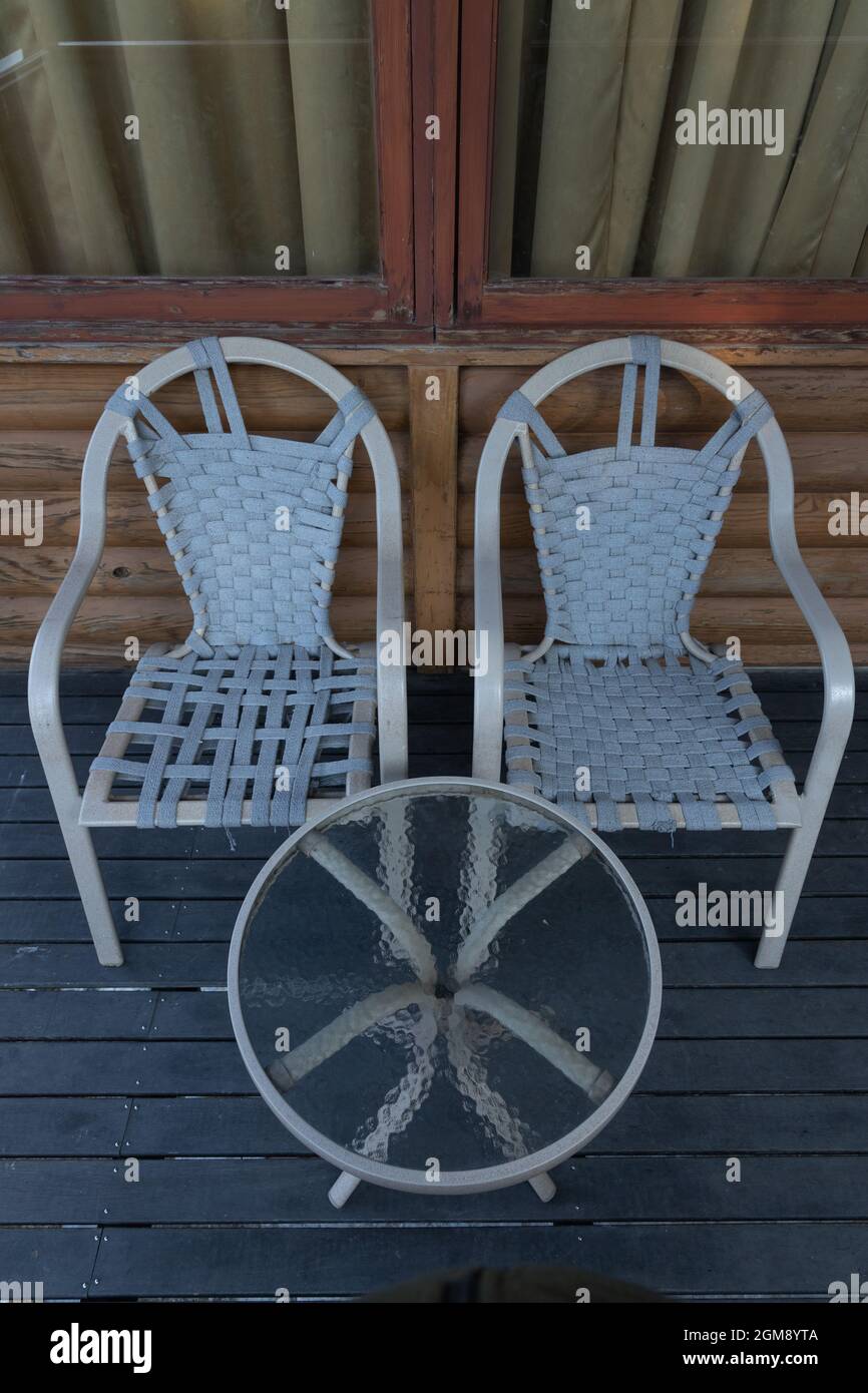 Ein Paar Stühle neben einem runden Tisch mit Glasplatte und Holz-Finish Hintergrund gehalten Stockfoto