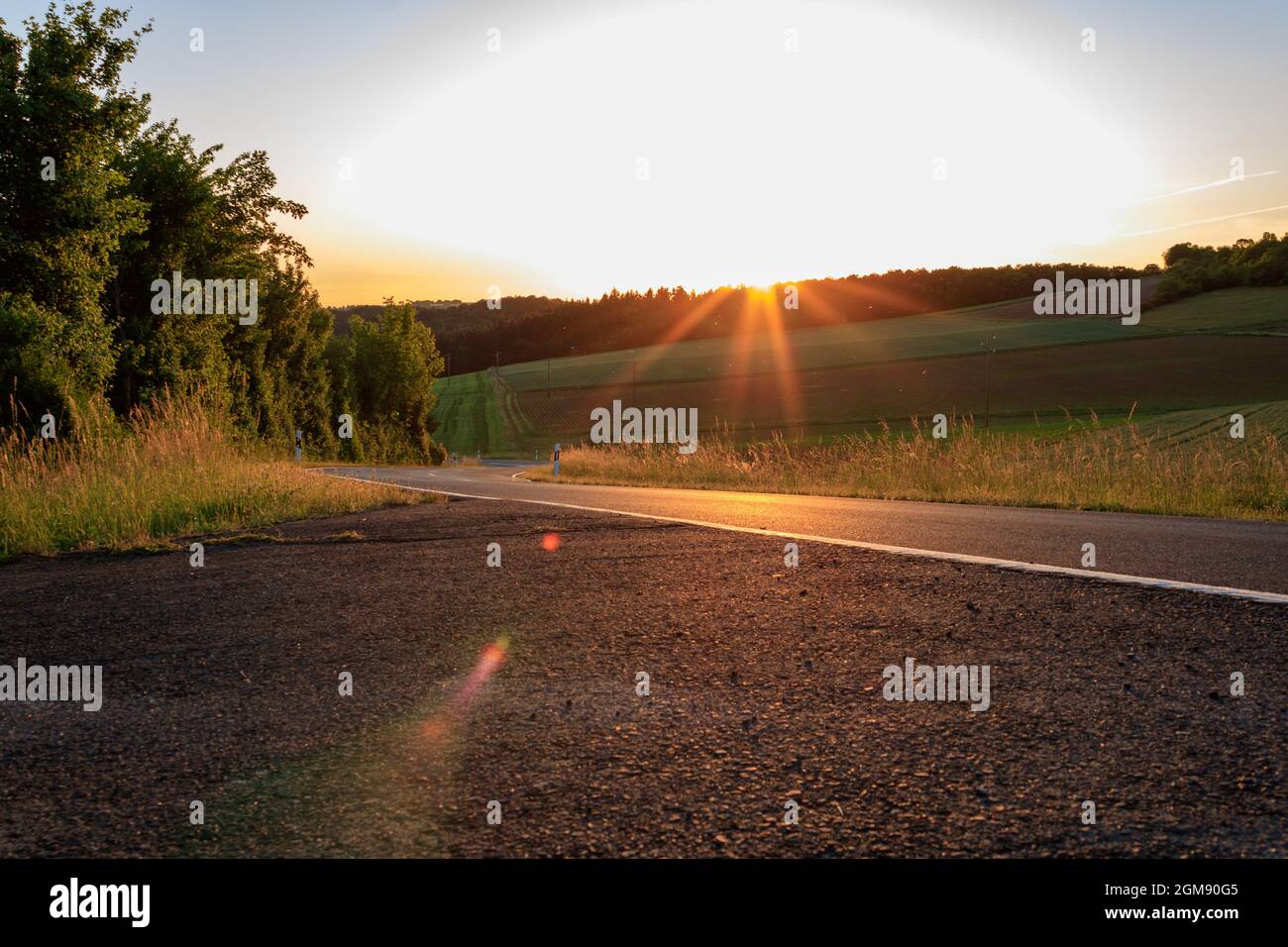 Sonnenuntergang über der Straße in ländlicher Landschaft im Sommer im Taubertal, Deutschland Stockfoto