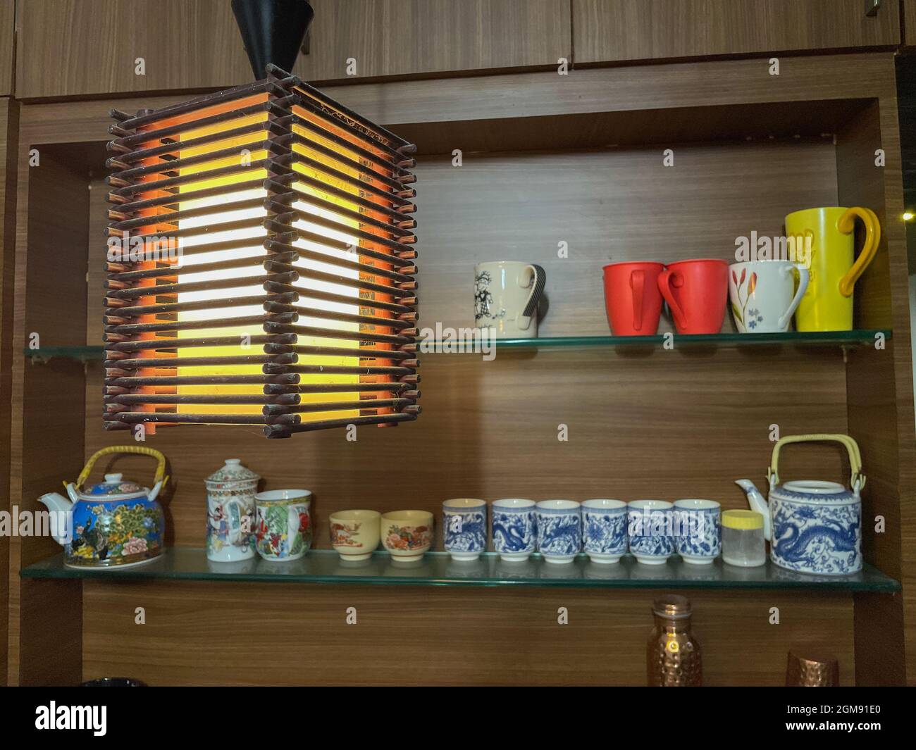Bunte Porzellan und Keramik Tassen und Tassen mit Designs auf ihnen ordentlich in einem Holzregal angezeigt Stockfoto