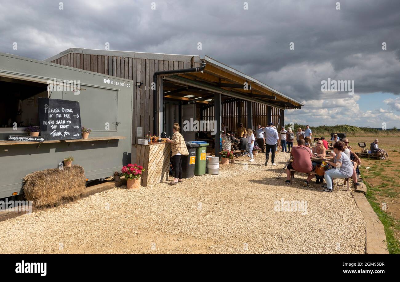 Chipping Norton, Oxfordshire, England, Großbritannien. 2021. Die Scheune und die Kunden essen und trinken von der Bar im Diddly Squat Farm Shop in der Nähe von Chipping Norton i Stockfoto