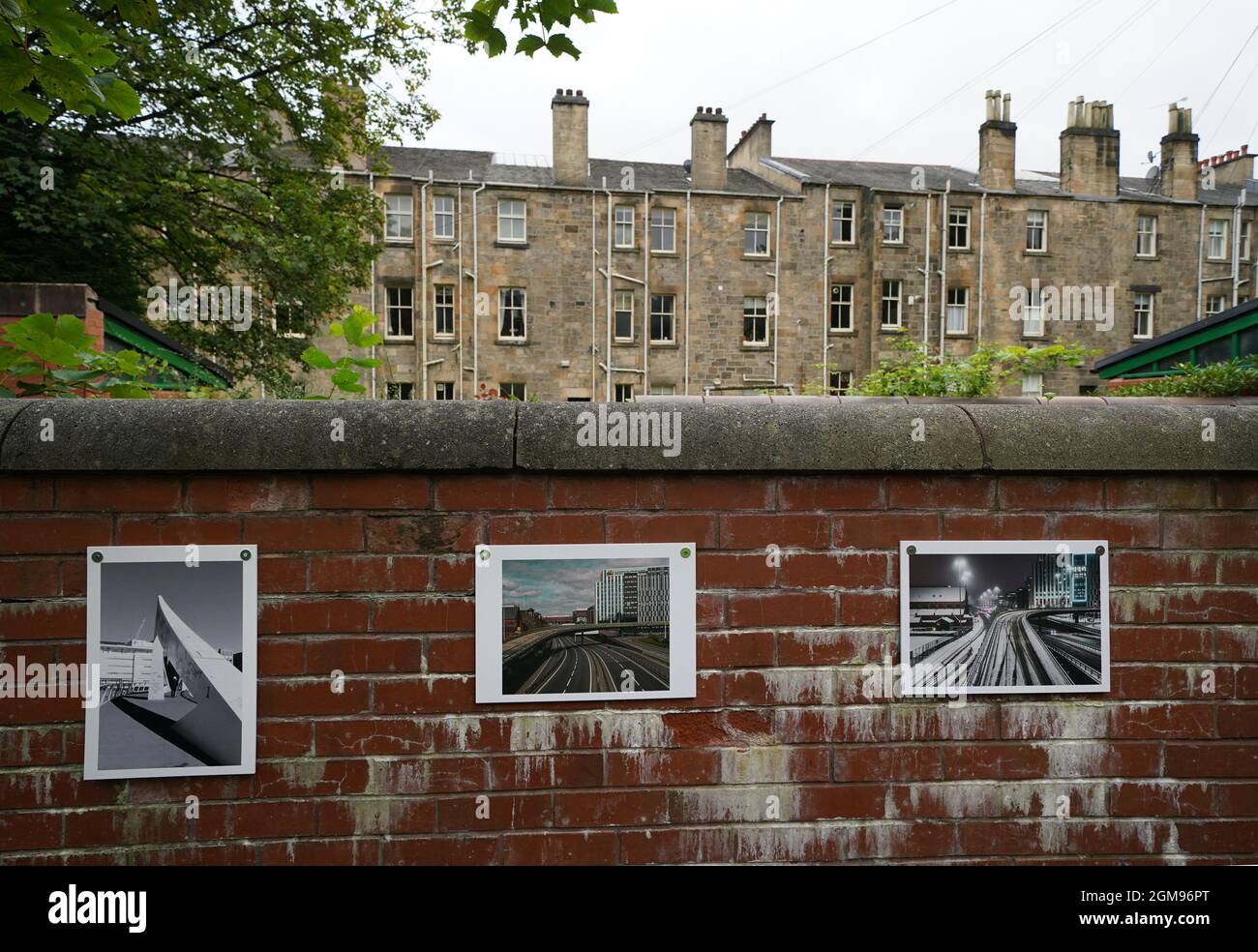 Fotografien, die an einer Wand angebracht sind und Teil einer Ausstellung sind, die die Covid-19-Sperre von 2020 dokumentiert, die in einem Mietsgarten in Pollokshields, Glasgow, der Öffentlichkeit gezeigt wird. Bilddatum: Freitag, 17. September 2021. Stockfoto