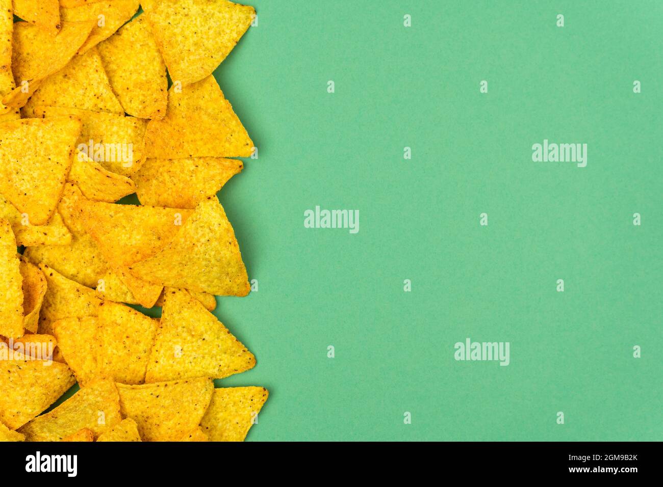 Tortilla-Mais-Chips sind auf einem farbigen Hintergrund mit Platz für Text verstreut. Stockfoto