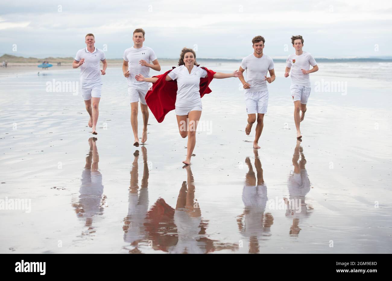 St Andrews, Großbritannien. 17. September 2021: Nachbildung des berühmten Chariots of Fire-Rennens am West Sands, Mitglieder des Tennisclubs von St Andrews, die die University of St Andrews feiern, die zur Nummer 1 der Universität in Großbritannien ernannt wurde, Zum ersten Mal in The Times und Sunday Times Good University Guide 2022 (von links nach rechts): Mark Brocklebank, Fin Pearson, Lily Turner (mit dem legendären roten Undergraduate-Kleid von St. Andrews), Gregory Dritschel und Timothy Moore. Kredit: Gayle McIntyre/Alamy Live Nachrichten Stockfoto