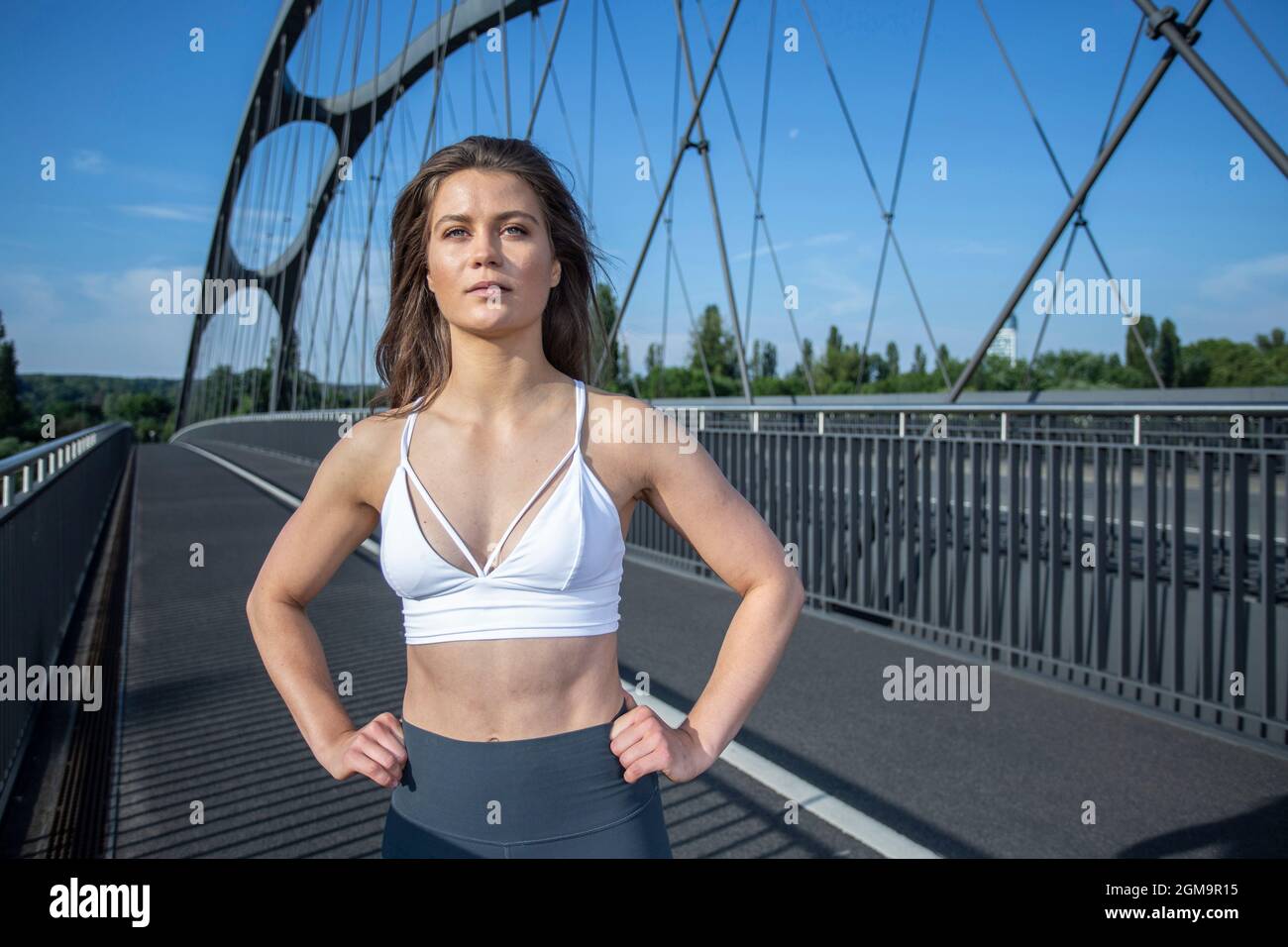 Junge Frau, die an sonnigen Tagen Yoga auf der Straße in Frankfurt am Main, Hessen, Deutschland, durchführt. Stockfoto