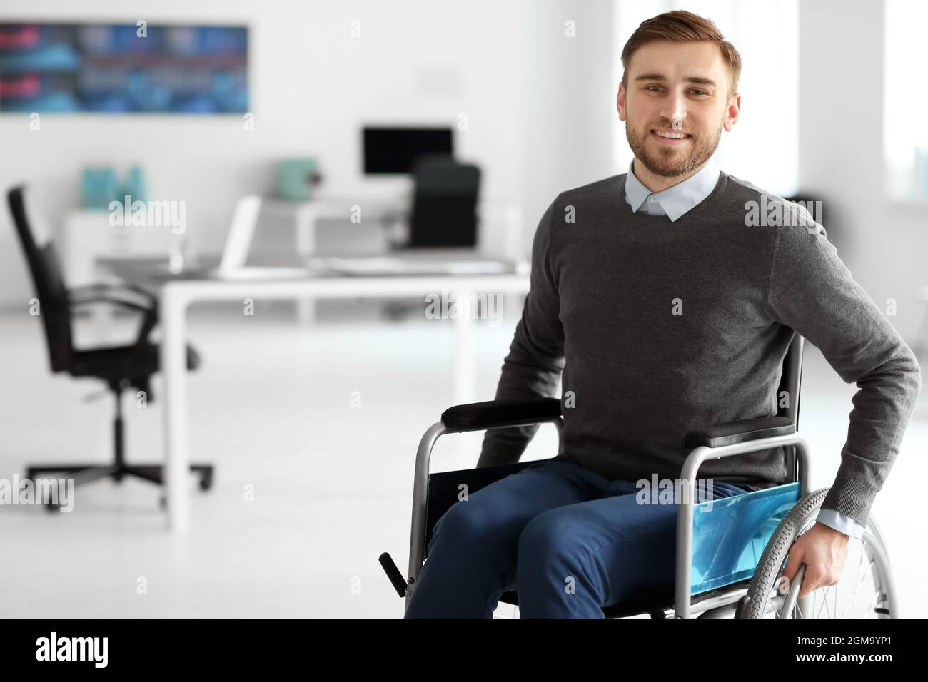 Junger Mann im Rollstuhl am Arbeitsplatz Stockfoto