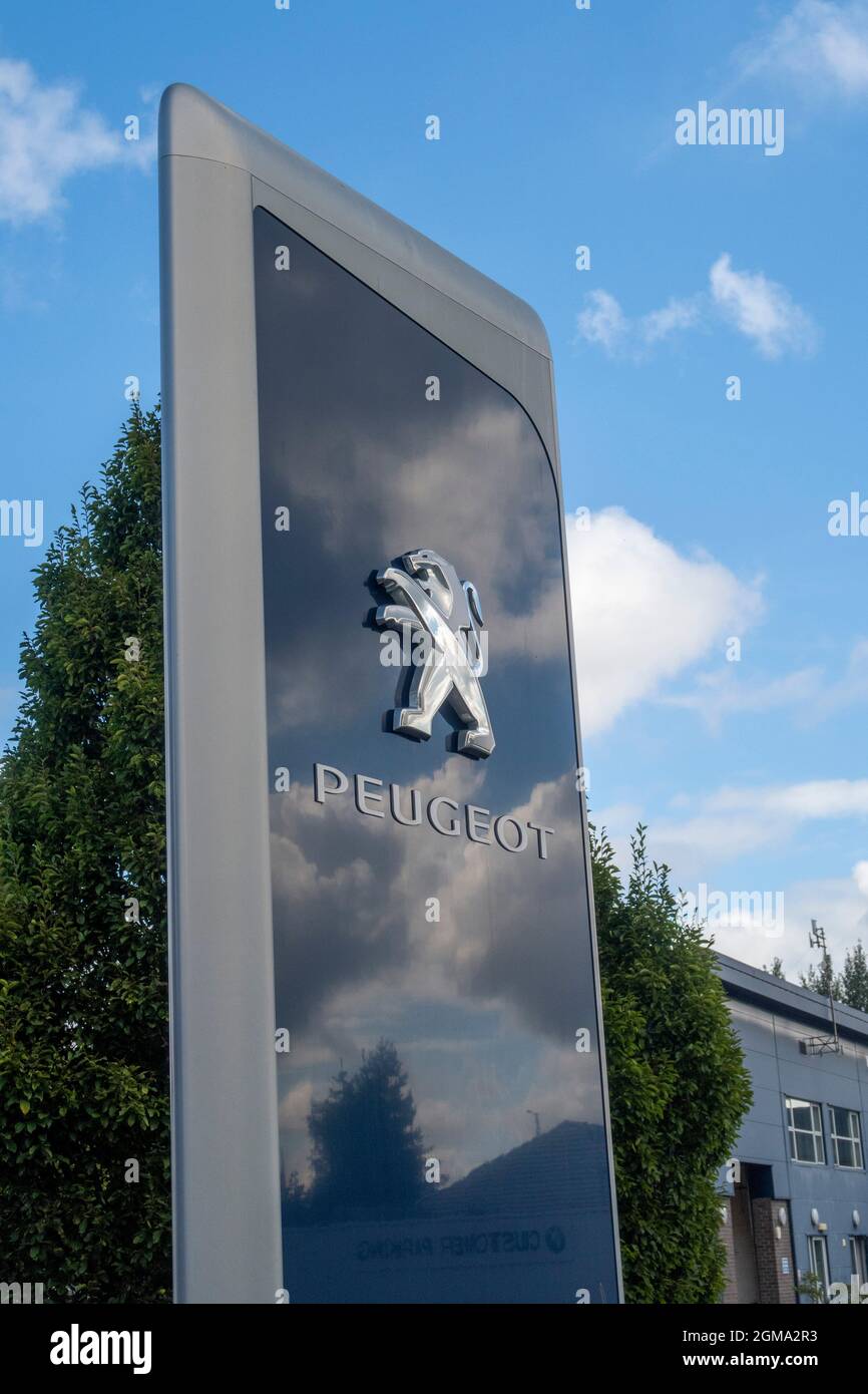 Peugeot Auto-Logo und Schild vor dem Autohändler-Showroom, Exeter Stockfoto