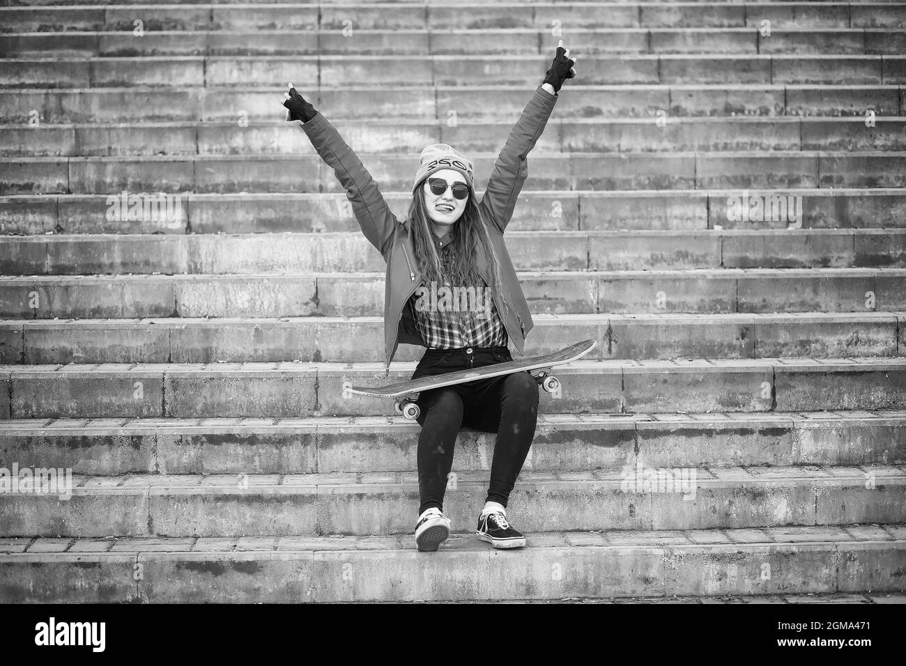 Ein junger Hippie girl reitet ein Skateboard. Mädchen Freundinnen für einen Spaziergang in der Stadt mit einem Skateboard. Frühling Sport auf der Straße mit einem Skateboard. Stockfoto