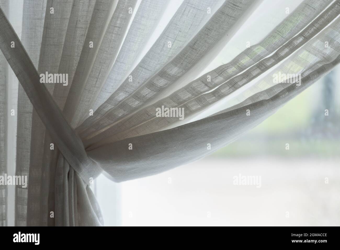 Welliger Tüll vor dem hellen Fenster. Hintergrundfoto mit selektivem Weichfokus Stockfoto