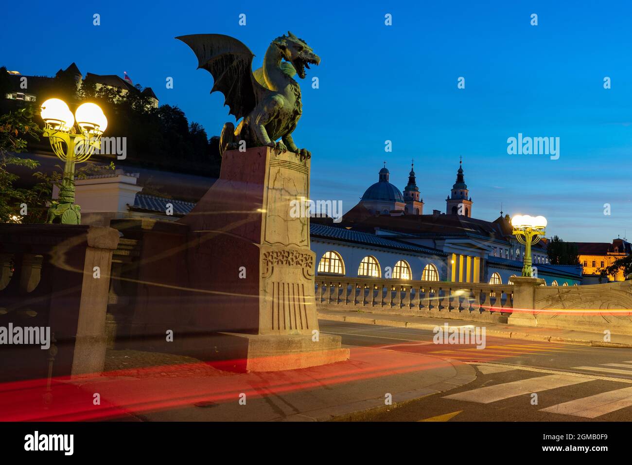 Drachenbrücke in Ljubljana bei Nacht mit Kathedrale Hintergrund und lange Belichtung Stadtlichter . Stockfoto