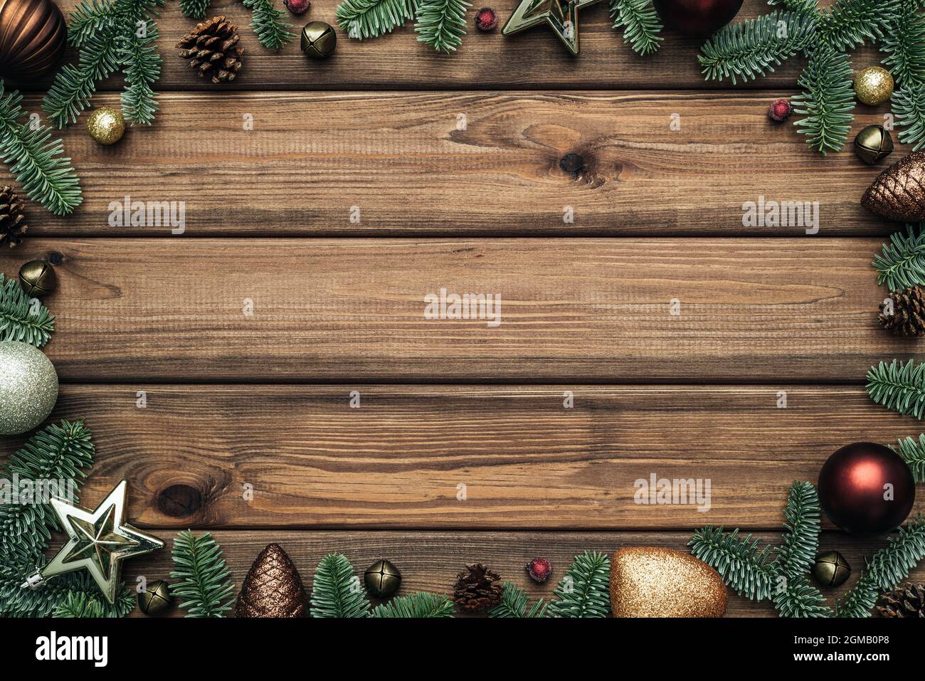 Weihnachtshintergrund mit Rahmen aus Tannenzweigen und Kugeln auf Holzhintergrund. Flach liegend, Draufsicht und Platz zum Kopieren von Text Stockfoto