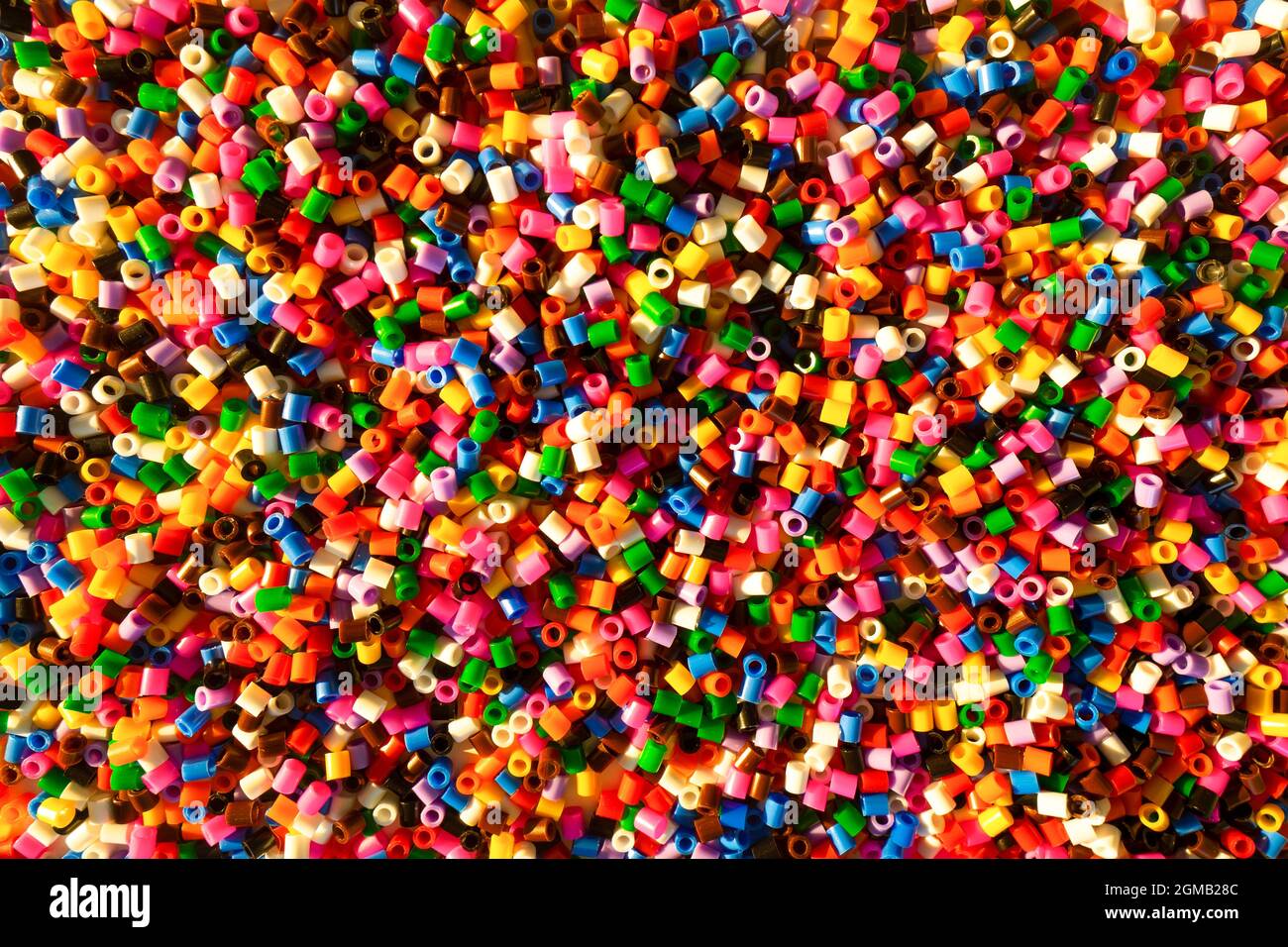 Bunte kleine Plastikperlen bilden den lebendigen Hintergrund. Set aus kleinen bunten, lebendigen Bastelelementen. Stockfoto