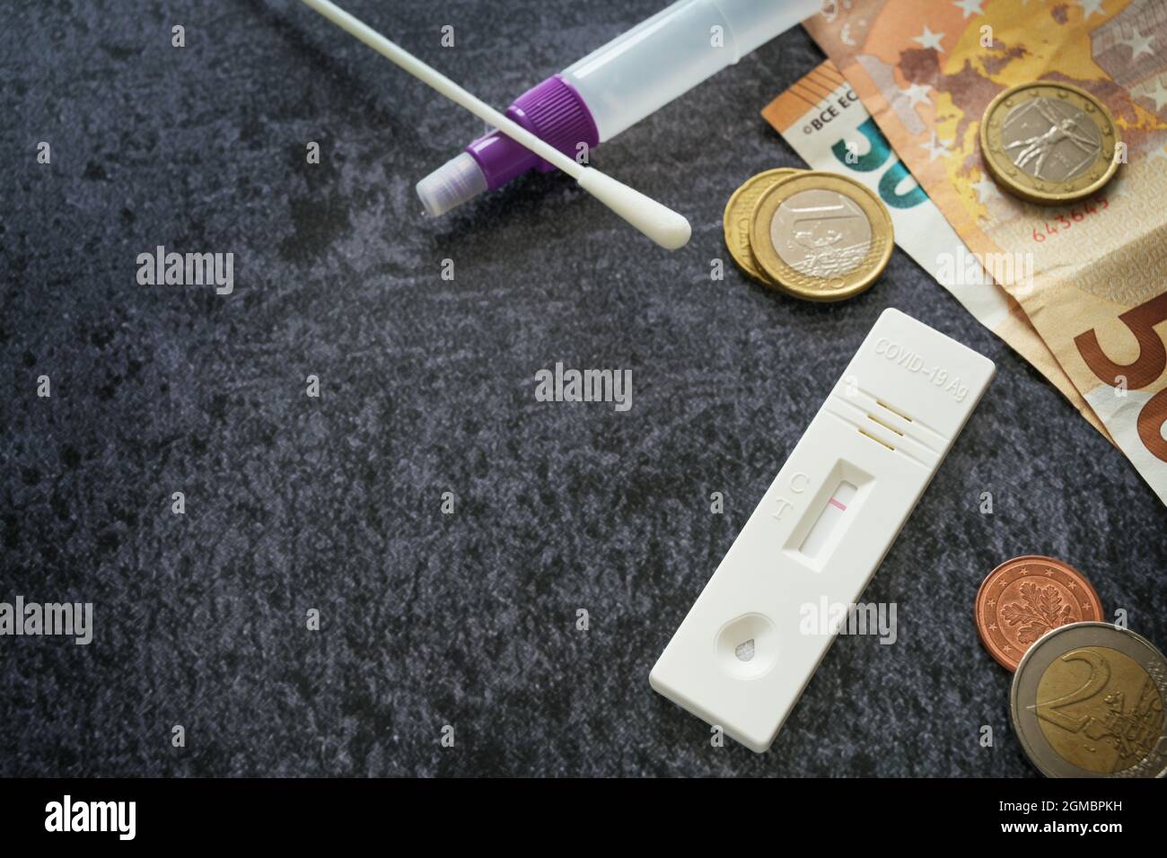 Erforderlicher covid-19 Schnelltest-Kit und Euro-Geld, Kosten für die Gesundheitsversorgung und Sicherheit, die während der Coronavirus-Pandemie am öffentlichen Leben teilnehmen, dunkelgrau Stockfoto