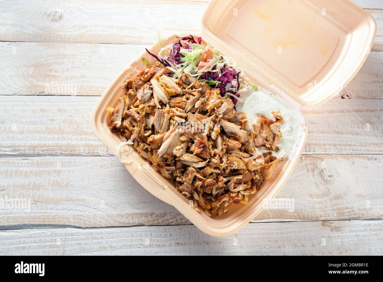 Fastfood in einer Take-Away-Box aus Styropor, Döner Kebab mit Hühnerfleisch, Salat und Dip auf einem Holztisch, Kopierraum, Hochwinkel von oben, s Stockfoto