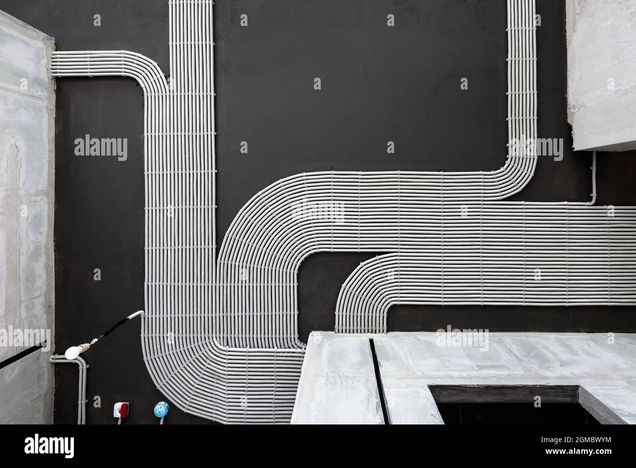 Elektrokabel und Rohre auf dem Hintergrund der Betondecke des Hauses, Kunststoffschläuche mit Drähten im leeren Raum. Leitungen von pvc-Leitungen nach professionellen Stockfoto