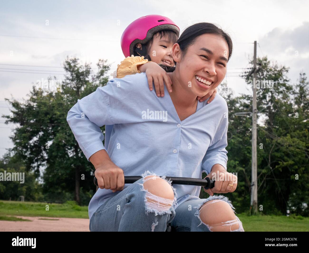 Glückliche Mutter genießen Spaß Reiten Kinder Fahrrad mit niedlichen Tochter im Sommer Park. Die Familie verbringt ihre Freizeit zusammen im Urlaub. Stockfoto
