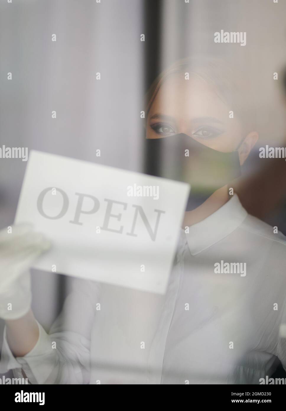 Wiedereröffnung des Geschäfts nach einer Pandemie durch eine junge Frau in Gesichtsmaske Stockfoto