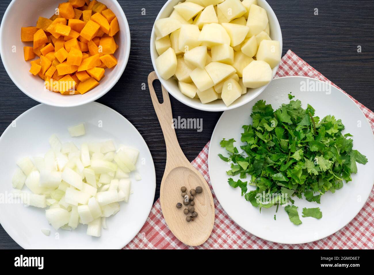 Zutaten für Suppe, Draufsicht auf Karotte, Zwiebel, Kartoffel, Koriander, Pfeffer in weißen Keramikplatten, Gemüseset Stockfoto