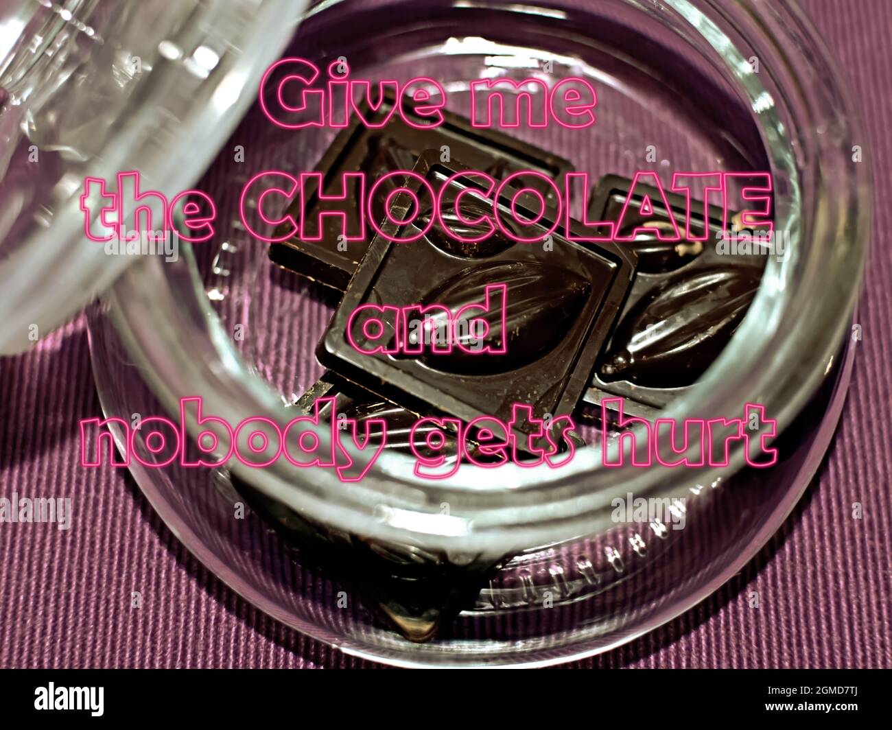 Positives Zitat über die Liebe zur Schokolade. Gebt mir die Schokolade und niemand wird verletzt. Botschaft auf dem Hintergrund eines Glasglases mit Süßigkeiten. Getönte imag Stockfoto