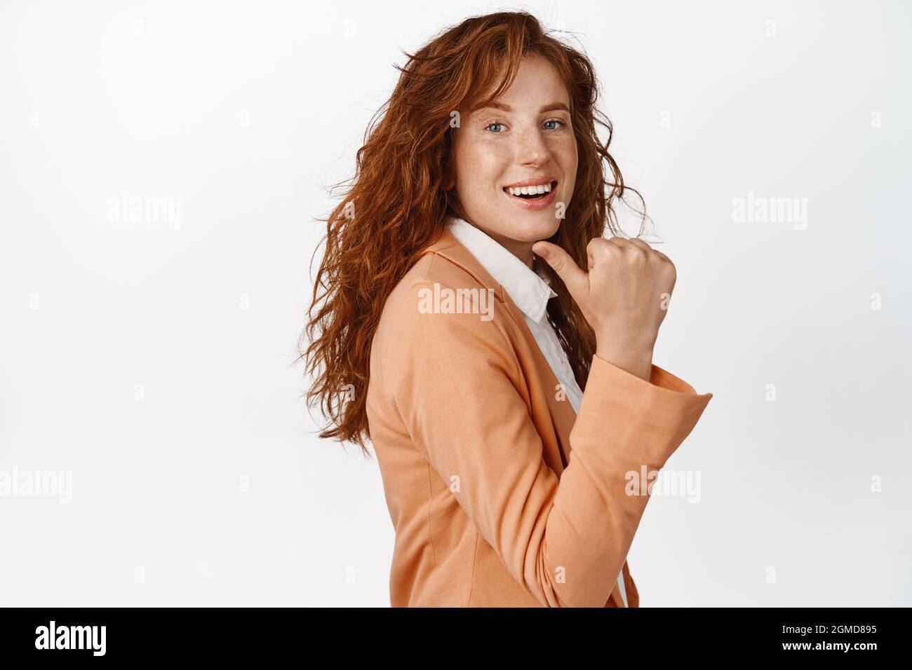 Selbstbewusste Verkäuferin zeigt nach links, zeigt Rabatt- oder Firmenlogo hinter ihrem Rücken, zeigt Werbung, steht in Anzug gegen Weiß Stockfoto