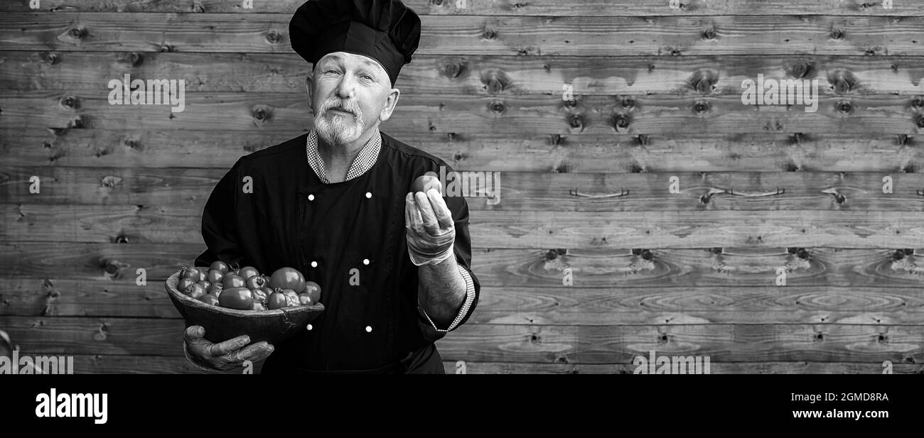Landwirt in Uniform mit frischem Gemüse auf einem Holzboden Stockfoto