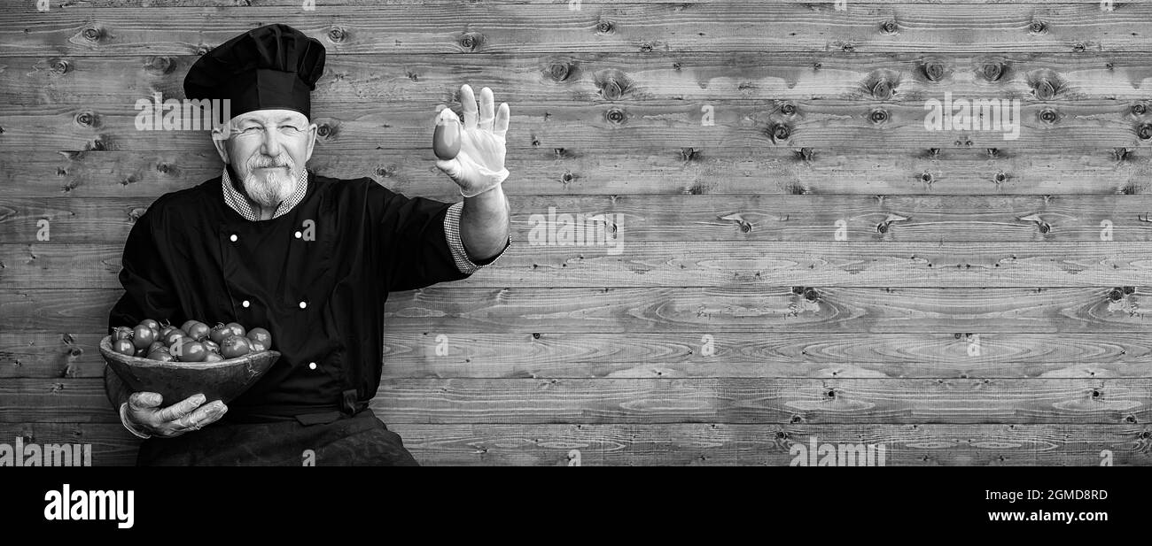 Landwirt in Uniform mit frischem Gemüse auf einem Holzboden Stockfoto