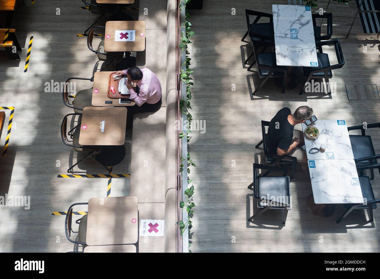 15.09.2021, Singapur, Republik Singapur, Asien - in einem Restaurant in einem Einkaufszentrum mit Tischen und Bänken, die aufgrund der Korona markiert sind, wird gespeist. Stockfoto