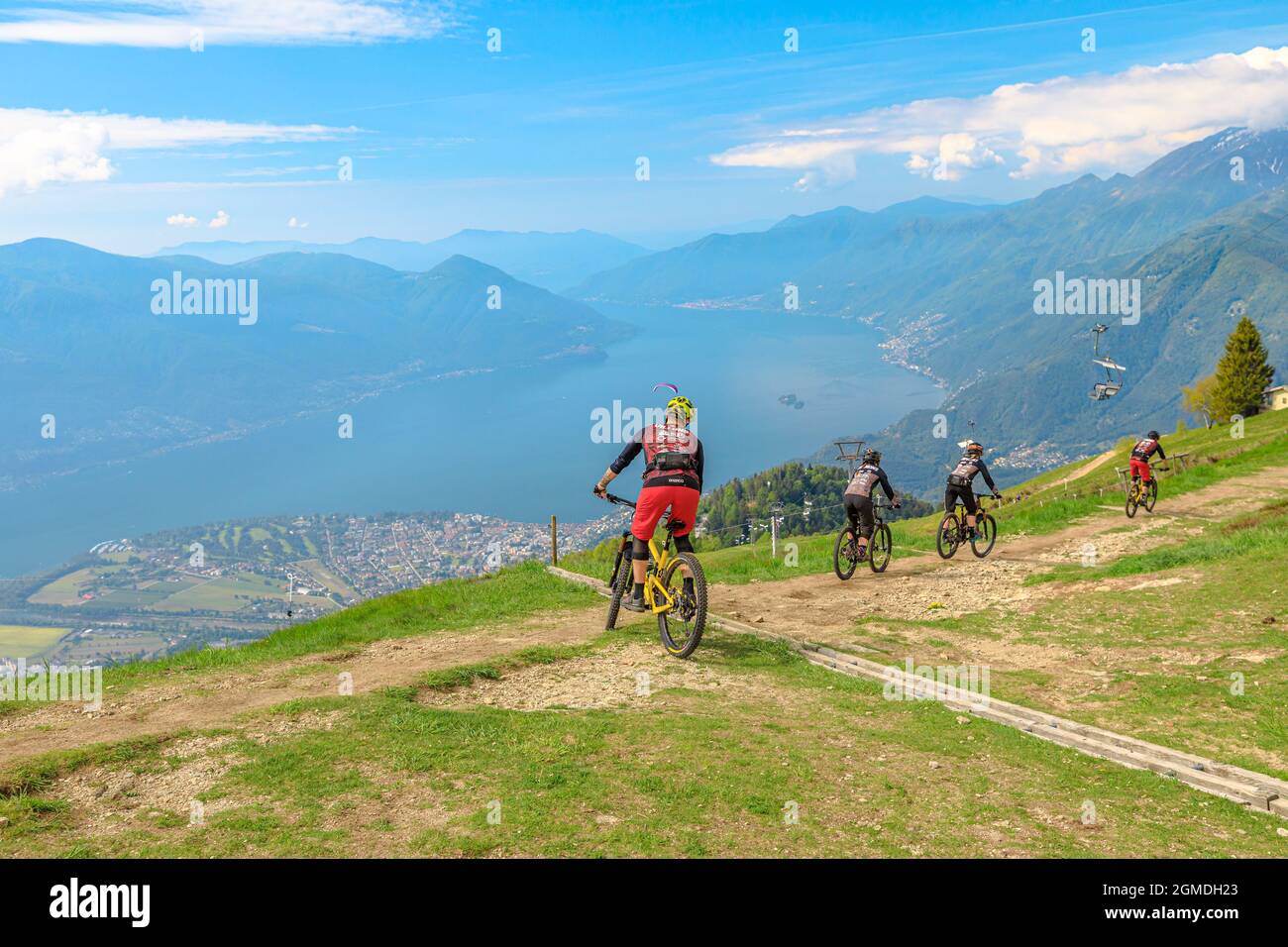 Verzasca, Schweiz - Juni 2021: Mountainbiker fahren vom Gipfel des Cardada-Cimetta-Gebirges in der Schweiz herunter. Schweizer Sessellift Skyline Stockfoto