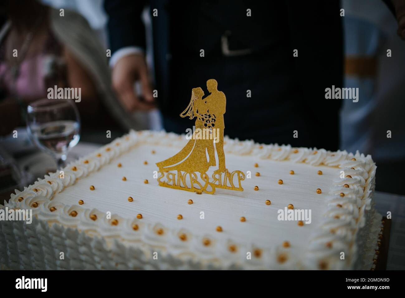 Hochzeitstorte mit goldenen Braut- und Bräutigam-Figuren darauf Stockfoto