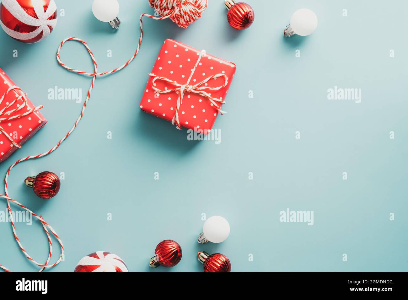 Vintage-Weihnachts-Postkarte. Flach liegend, Draufsicht gestreifte Kugeln, Band, Geschenkboxen auf blauem Hintergrund. Stockfoto
