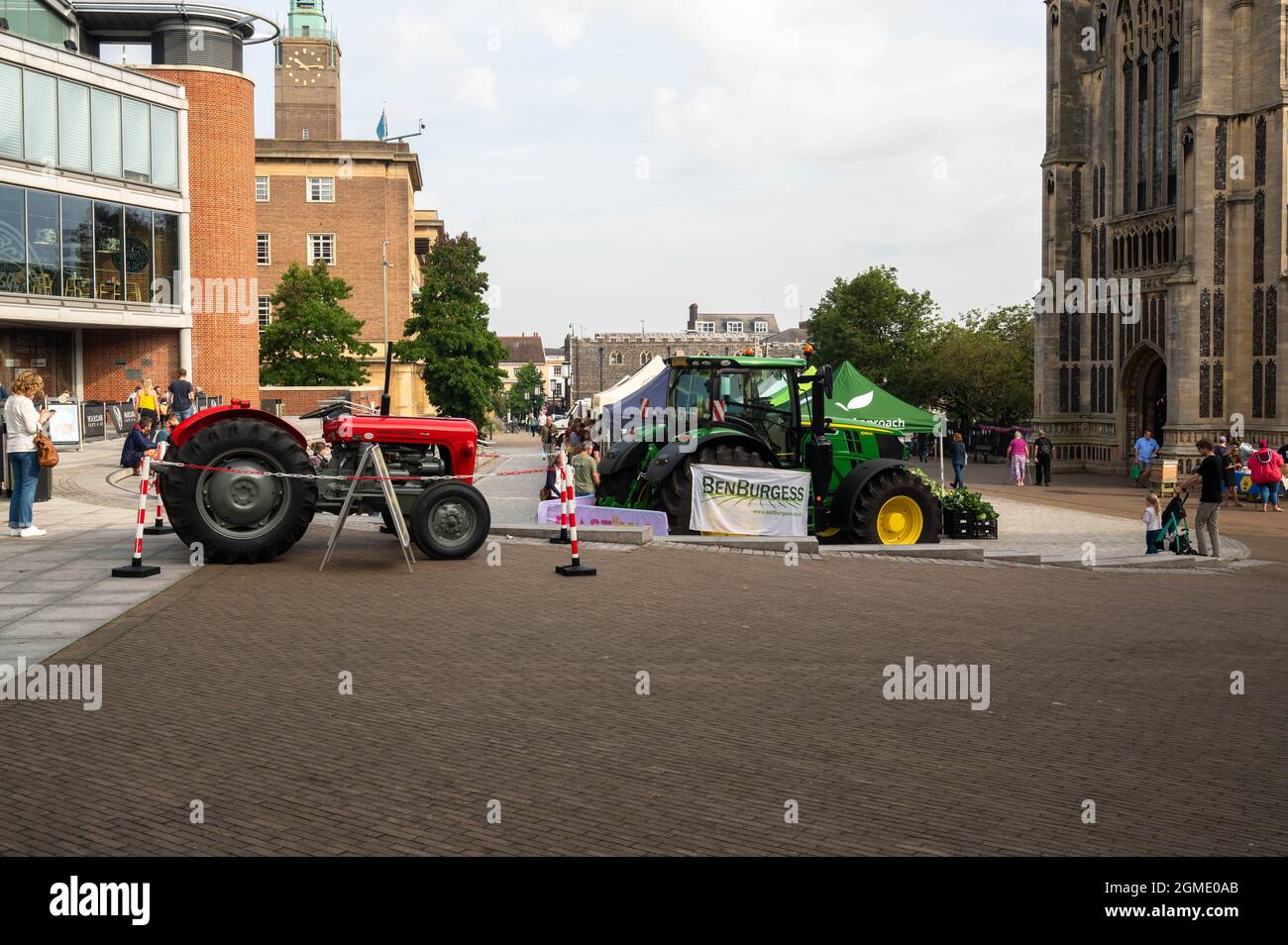 Blick auf einen kleinen roten Traktor neben einem großen grünen Traktor, der von der Firma Ben Burgess vor dem Forum norwich beworben wird Stockfoto