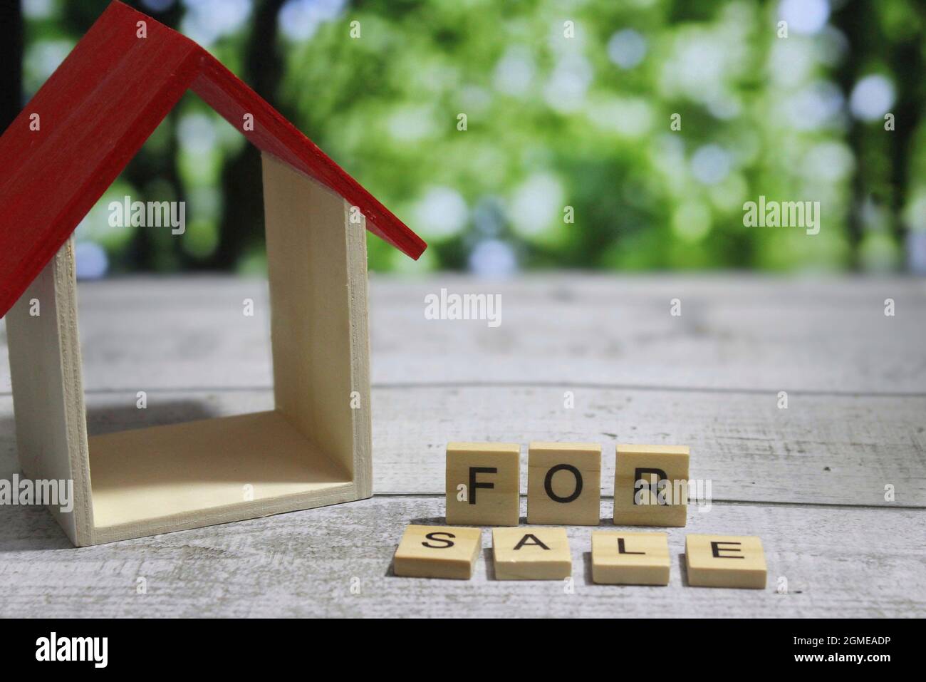 Selektives Fokusbild von Miniaturhaus und Holzwürfel mit Text ZUM VERKAUF. Unscharfer Hintergrund, Bokeh-Effekt. Stockfoto