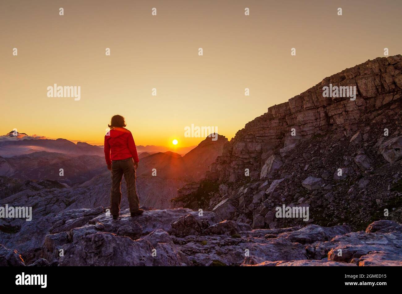 Die Wanderfrau auf dem Gipfel des Berges trifft auf die aufgehende Sonne. Konzept zur Erreichung des Lebensziels. Wanderlust und Outdoor-Aktivitäts-Konzept. Stockfoto