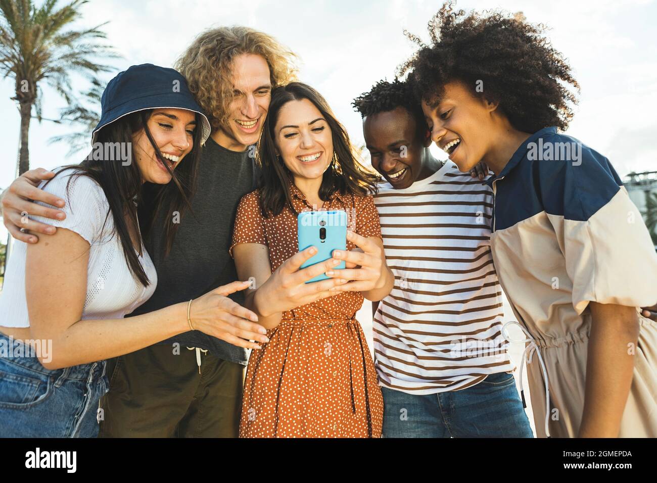 Multirassische Gruppe junger Menschen, die auf der Straße auf das Smartphone schauen. Stockfoto