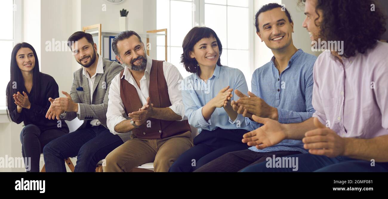 Gruppe lächelnder Personen, die ihren Kollegen oder Business Coach in einem Meeting applaudieren Stockfoto