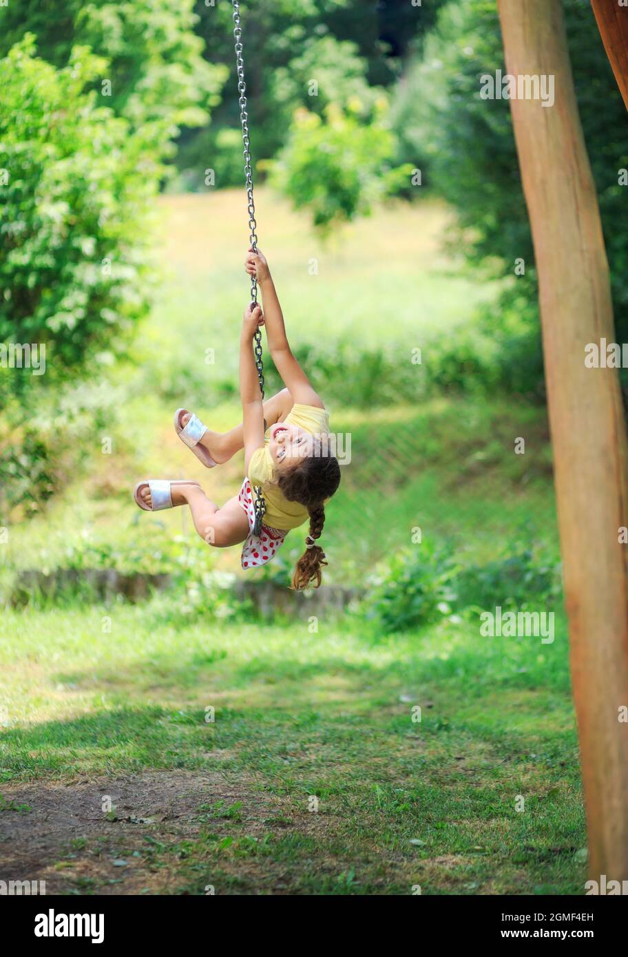 Portrait des schönen kleinen Mädchens schwingt und spielt im sonnigen Sommerpark. Stockfoto