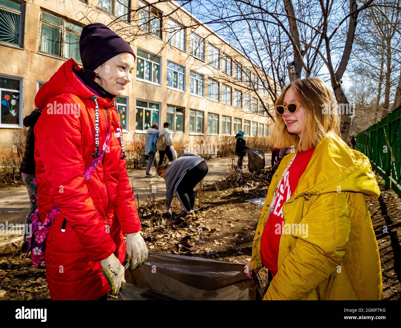 Omsk, Russland. 24. April 2021. Schülerinnen in roten und gelben Jacken halten einen Müllbeutel in der Hand. Traditionelle russische Veranstaltungen zur Vorbereitung der Schule Stockfoto