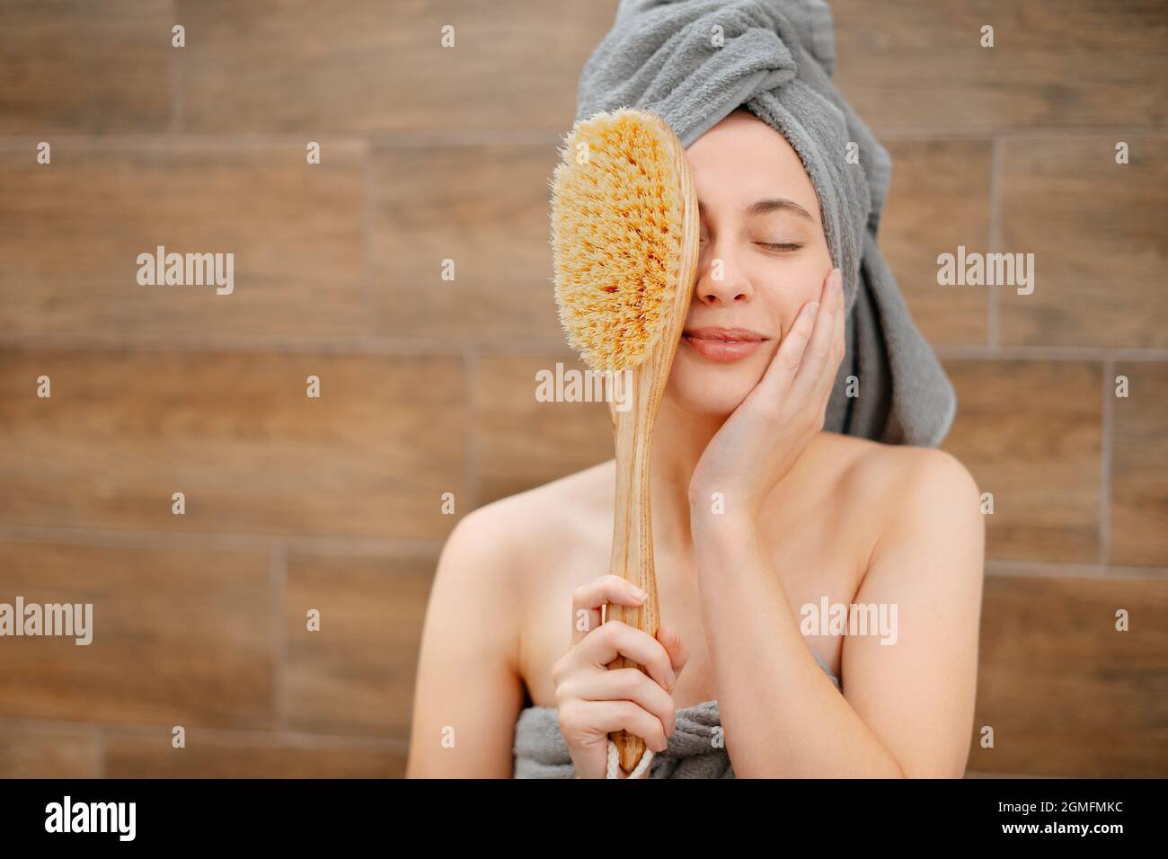 Frau im Badezimmer mit einer Holzbürste für die Körpermassage von Cellulite. Stockfoto