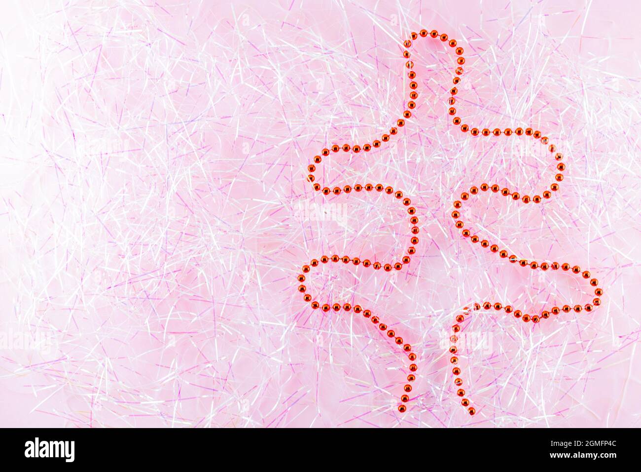 Symbol Weihnachten und Happy New Year Figur weihnachtsbaum mit roten Perlen auf Lametta. Weihnachtsperlen auf rosa Lametta. Urlaubskonzept. Draufsicht Stockfoto