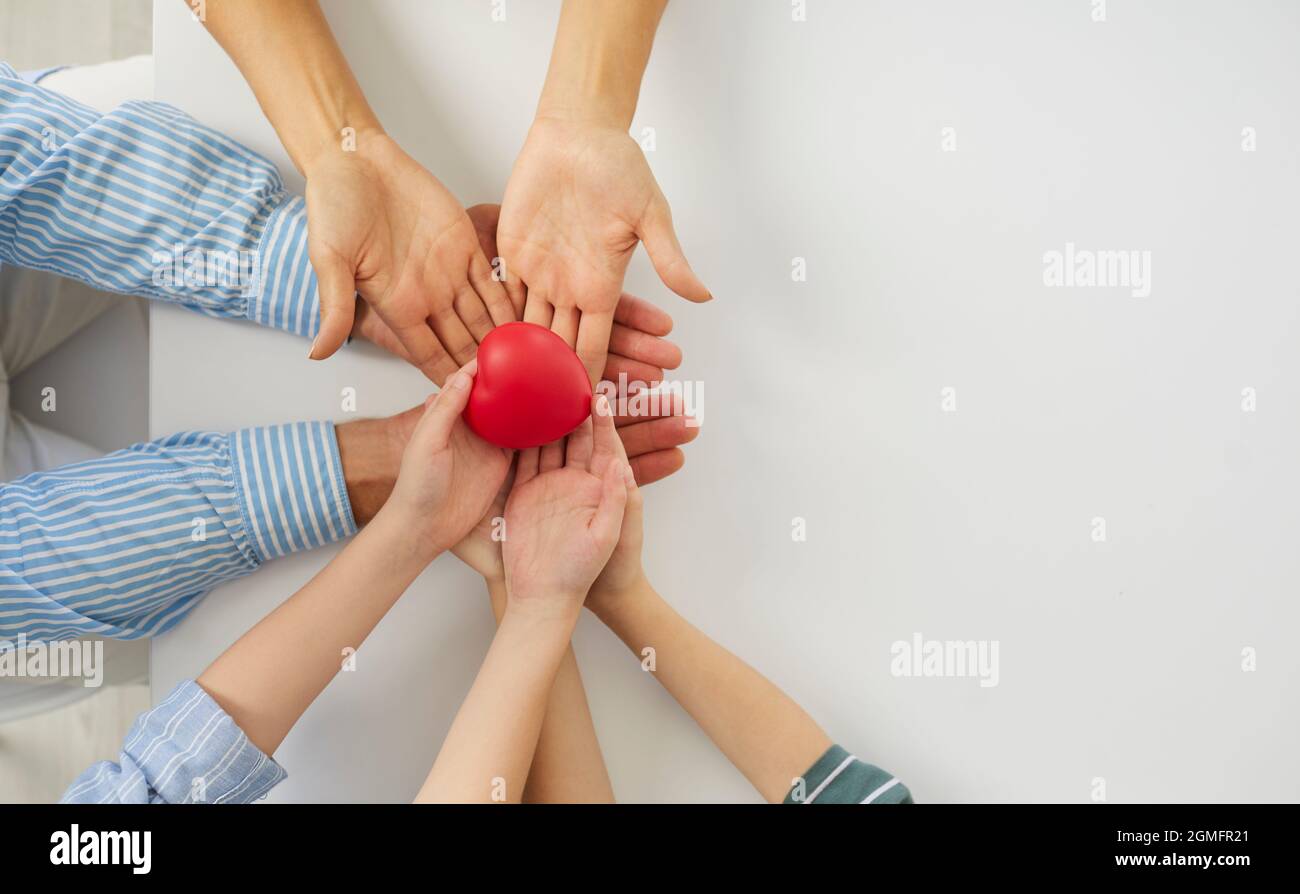 Liebevolle Familie, die das Herz in den Händen hält und Wohltätigkeit, Spende oder Herzgesundheit fördert Stockfoto