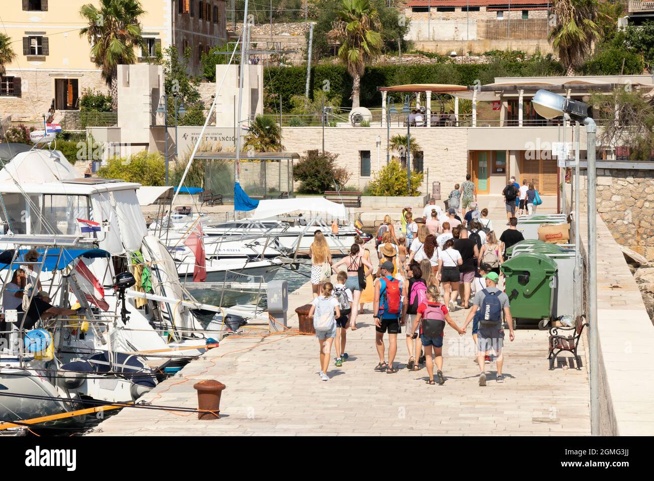 Prvic Luka, Kroatien - 25. August 2021: Junge Menschen gehen auf dem Pier in Richtung Gedenkstätte Faust Vrancic, Blick aus der Höhe Stockfoto