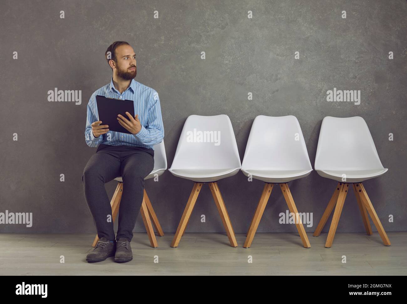 Gestresster kaukasischer Mann, der vor dem Vorstellungsgespräch auf einem Stuhl sitzt, Angst fühlt Stockfoto
