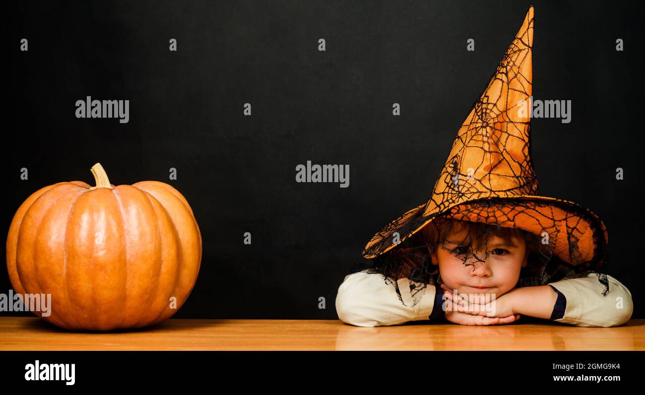 Niedliches Kind im Halloween Kostüm und Hexenhut mit Kürbis. Halloween Herbstferien. Stockfoto