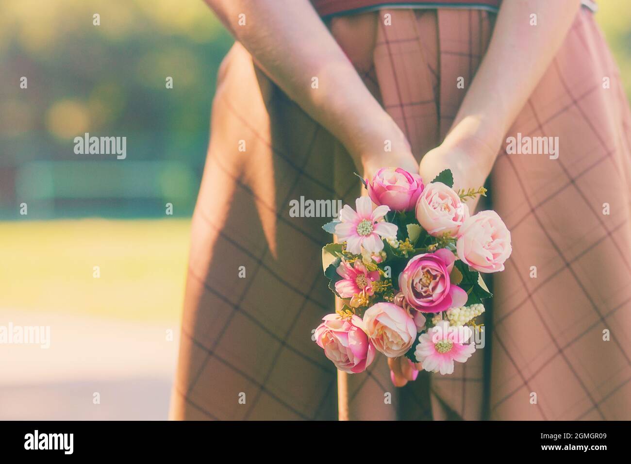 Kaukasisches Mädchen, das einen Blumenstrauß in den Händen auf dem Hintergrund eines grünen Sommersonnentages hält. Hochwertige Fotos Stockfoto