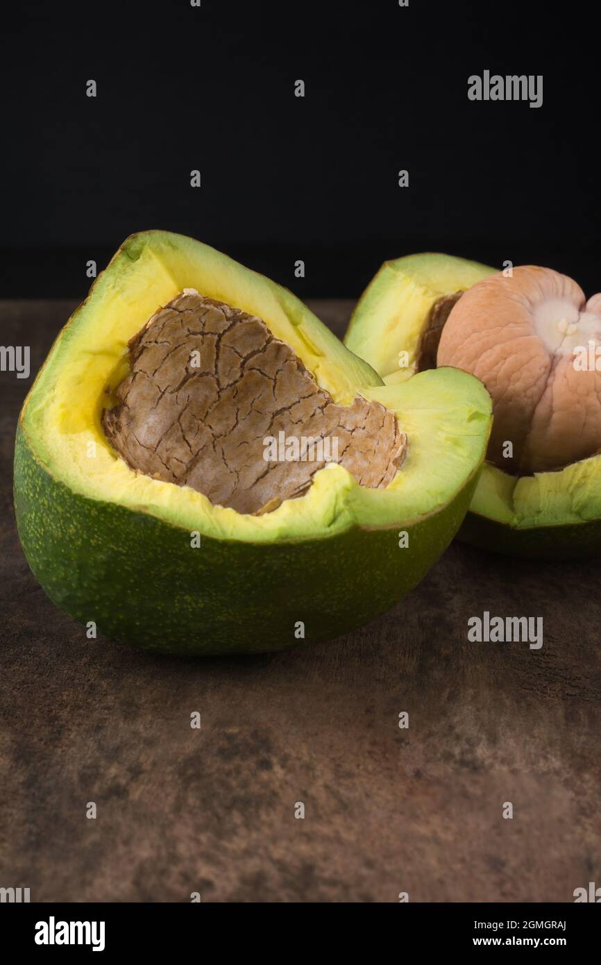 Avocados halbiert mit einem Samen, auch bekannt als Alligatorbirne oder Butterfrucht, frisches Obst auf einer holzstrukturierten Oberfläche, Nahaufnahme Stockfoto