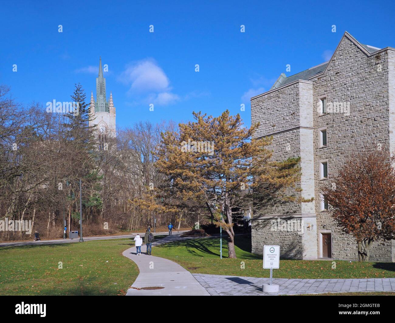 London, Ontario, Kanada - 4. Dezember 2018: Studenten wandern auf dem Campus der Western University in Richtung des Middlesex College-Uhrturms. Stockfoto